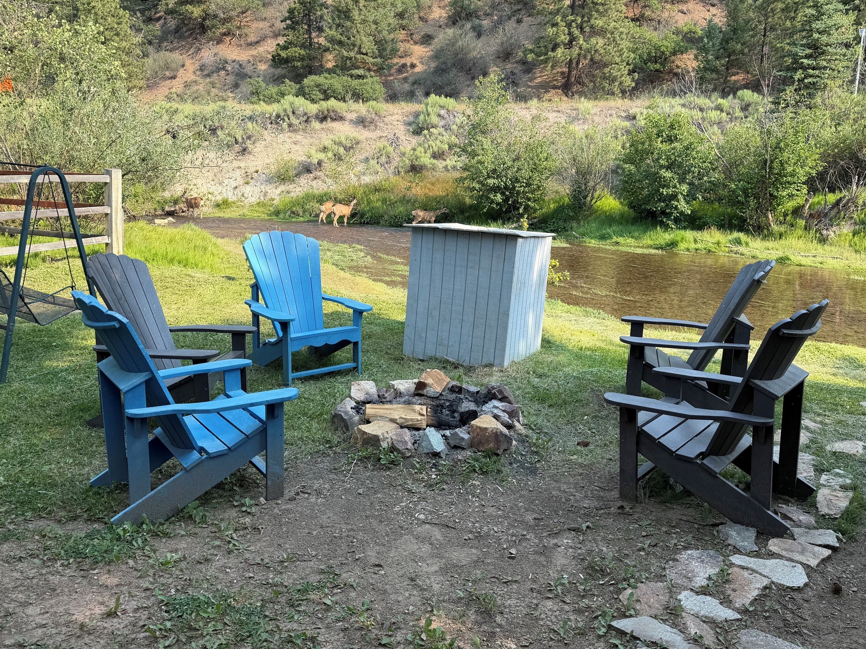 A patio area with Adirondack chairs, a fire pit, and a shed.