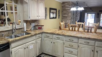 A kitchen with granite countertops, wooden cabinets, a dishwasher, and a fire extinguisher sign.