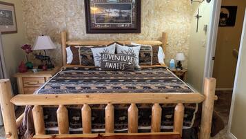 A wooden bed with a patterned bedspread and a pillow that reads "ADVENTURE AWAITS".