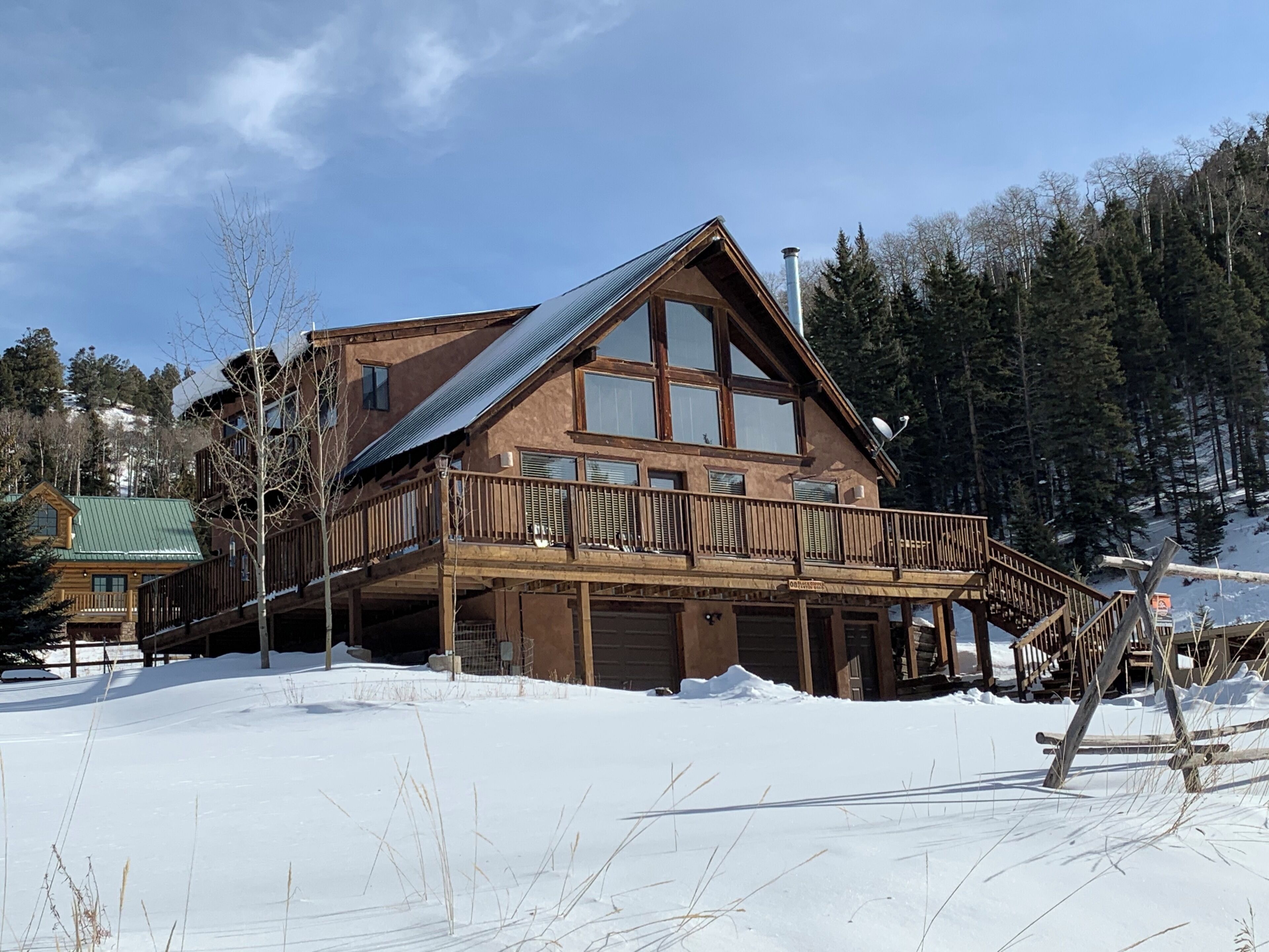 Una cabaña grande de madera con balcón, varias ventanas y un paisaje cubierto de nieve.