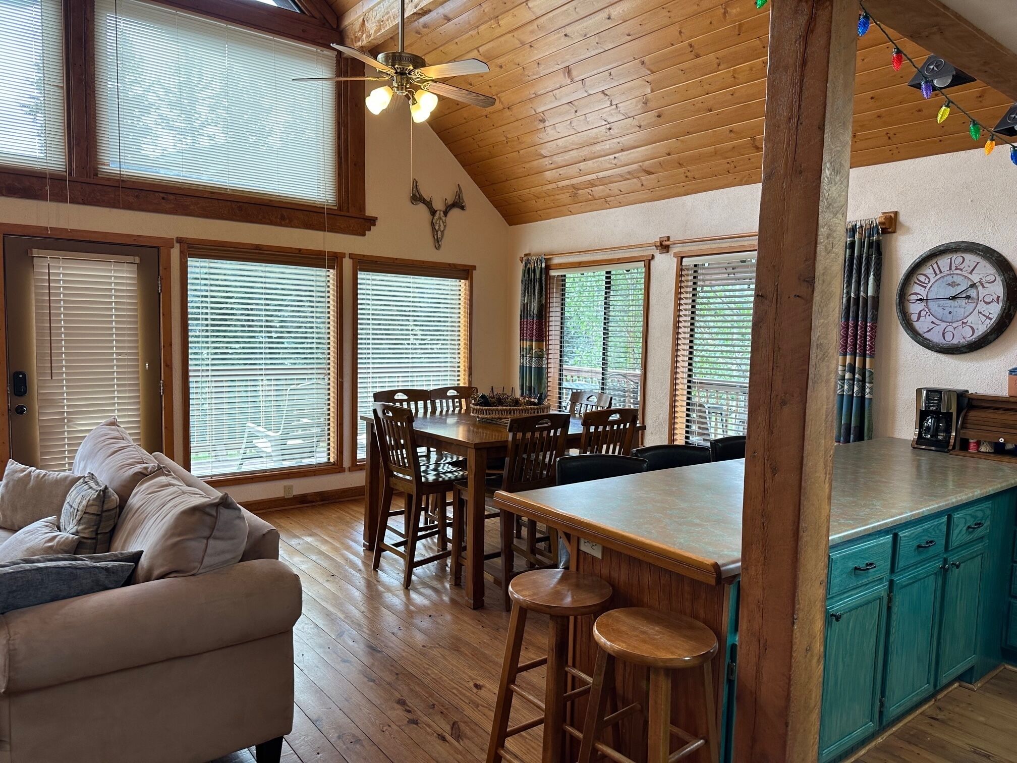 Un interior acogedor con zona de comedor, techo de madera y ventanas amplias.