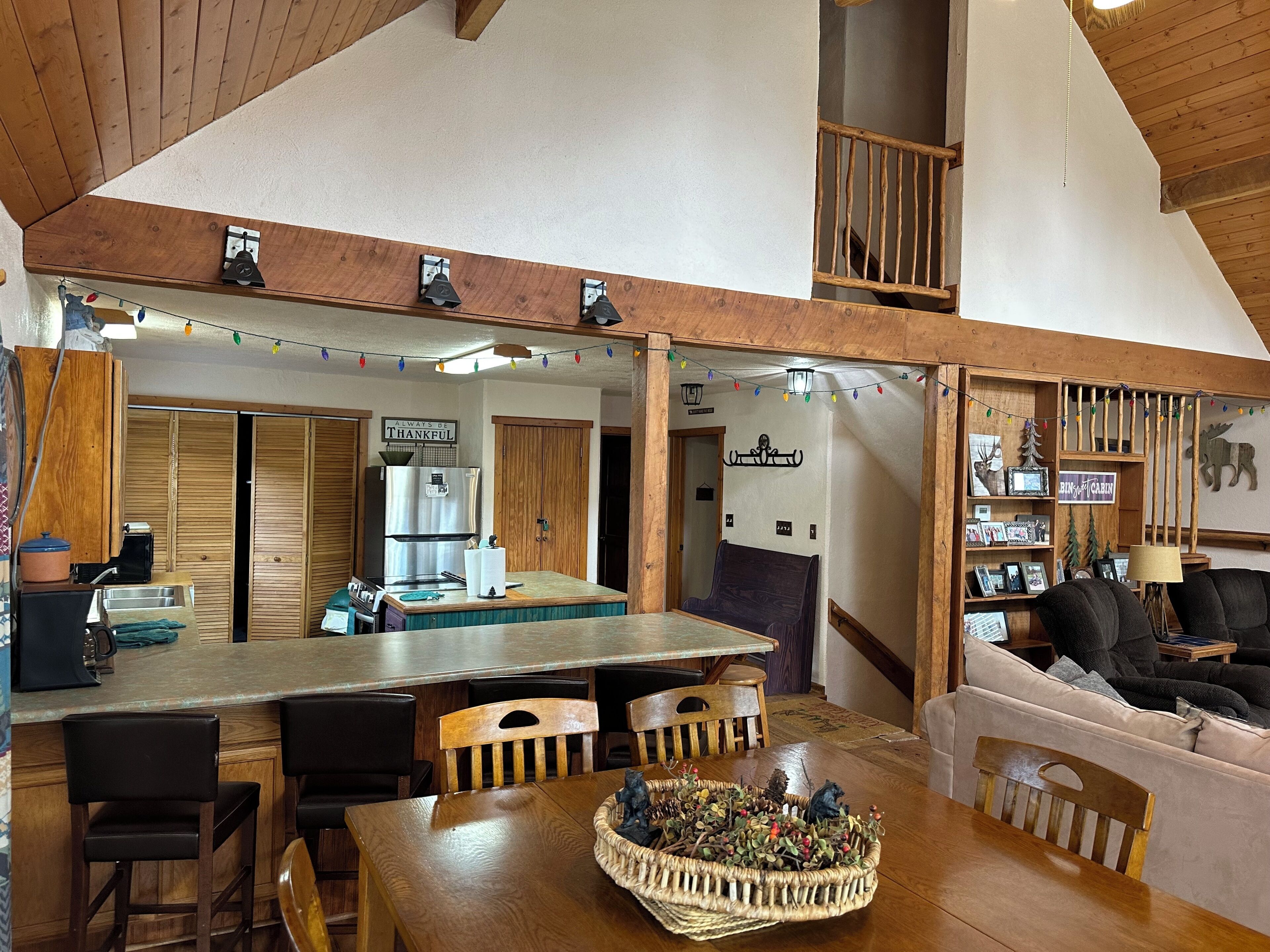 Una cocina acogedora con armarios de madera, un refrigerador de acero inoxidable, una mesa de comedor de madera con sillas y una isla de cocina.