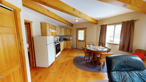 A cozy kitchen with wooden cabinets, a refrigerator, and a dining area with a table and chairs. - Round Eagle Home near the River and Park (Red River)