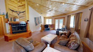 A spacious living room with a fireplace, comfortable seating, a television, and large windows. - Round Eagle Home near the River and Park (Red River)