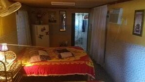 Um quarto aconchegante com uma cama, uma escrivaninha, um abajur, um frigorífico e um espelho.