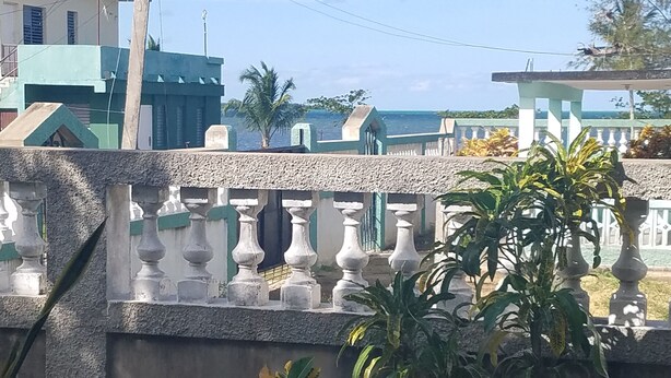 Varanda com guarda-corpo decorativo, vista de edifícios e vegetação.