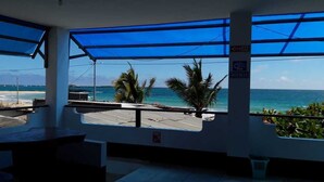 Un restaurant situé en bord de mer, doté de grandes fenêtres offrant une vue sur l’océan, d’un panneau indiquant la présence d’une connexion « Wi-Fi » et d’une poubelle de recyclage.