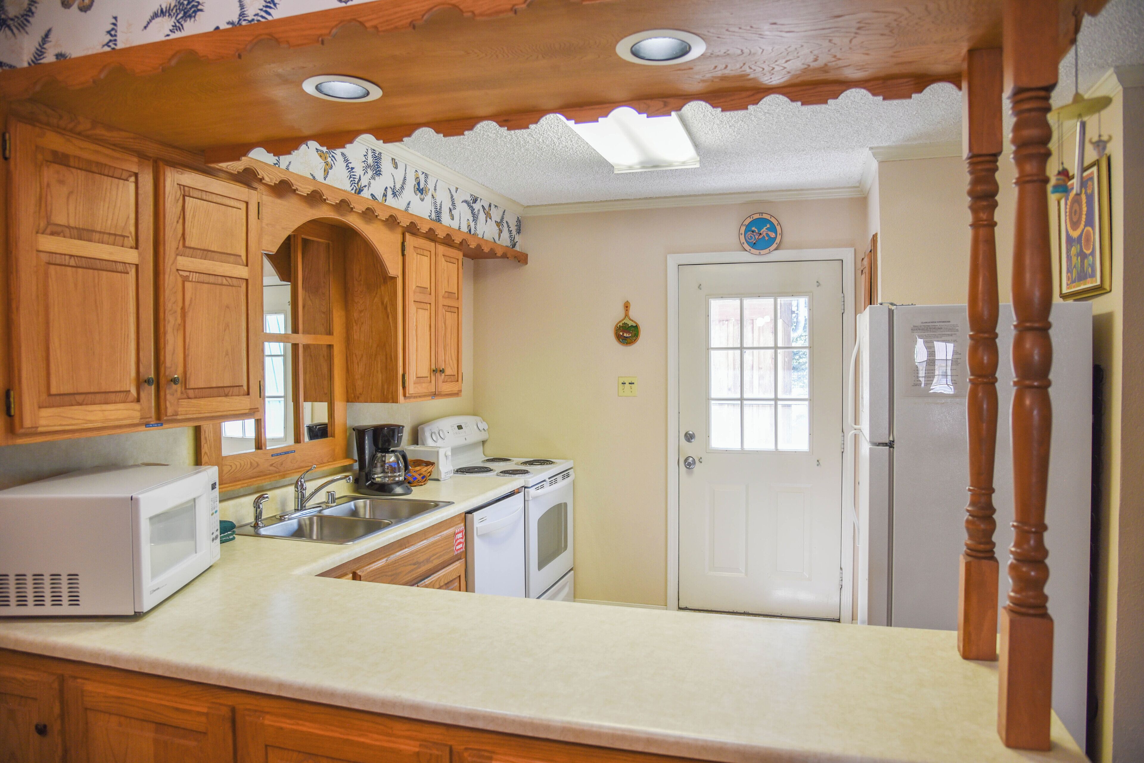 A kitchen with wooden cabinets, a white refrigerator, a microwave, and a stove.