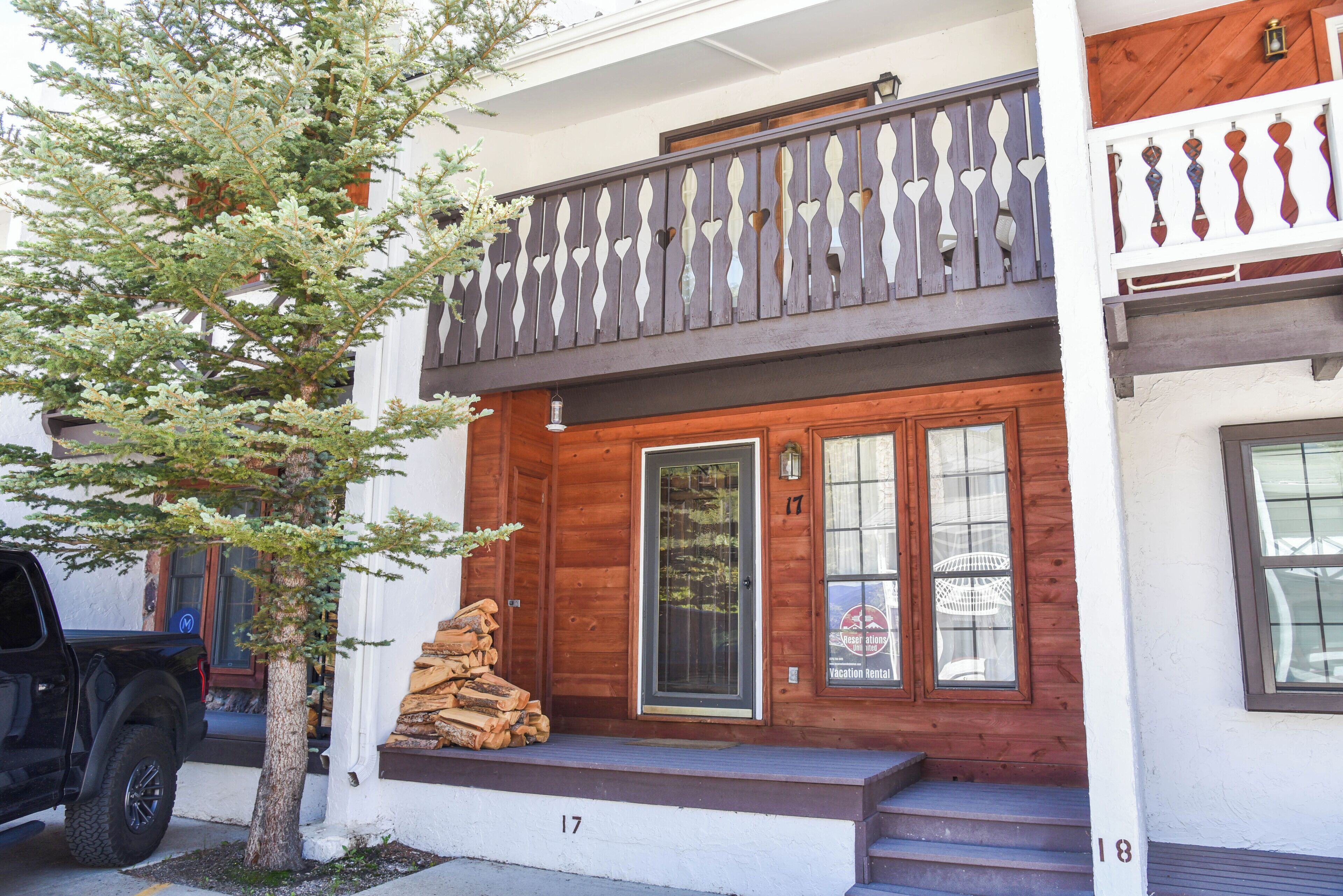 A two-story wooden house with a balcony, a front door, and a small porch area.