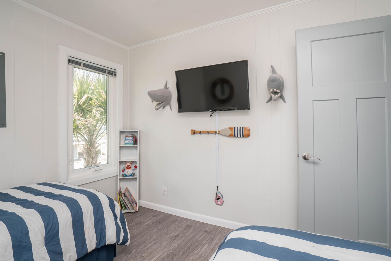 A bedroom with two beds, a TV mounted on the wall, and a door.