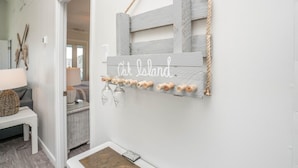 Un pasillo con decoración rústica que incluye un letrero de madera con la inscripción 'Oak Island' y varios tapones de vino.