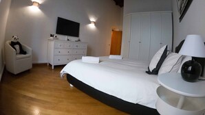 A bedroom with a bed, a dresser, a chair, a television, and a wardrobe.