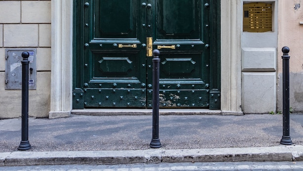 A green double door with ornate metalwork, set in a stone building with a number '45' plaque.
