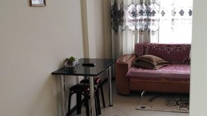 A small, well-lit room with a dining table and chairs, a sofa, and patterned rugs on the floor. - Kedr Grad Inn on the way to Medeo (Almaty)