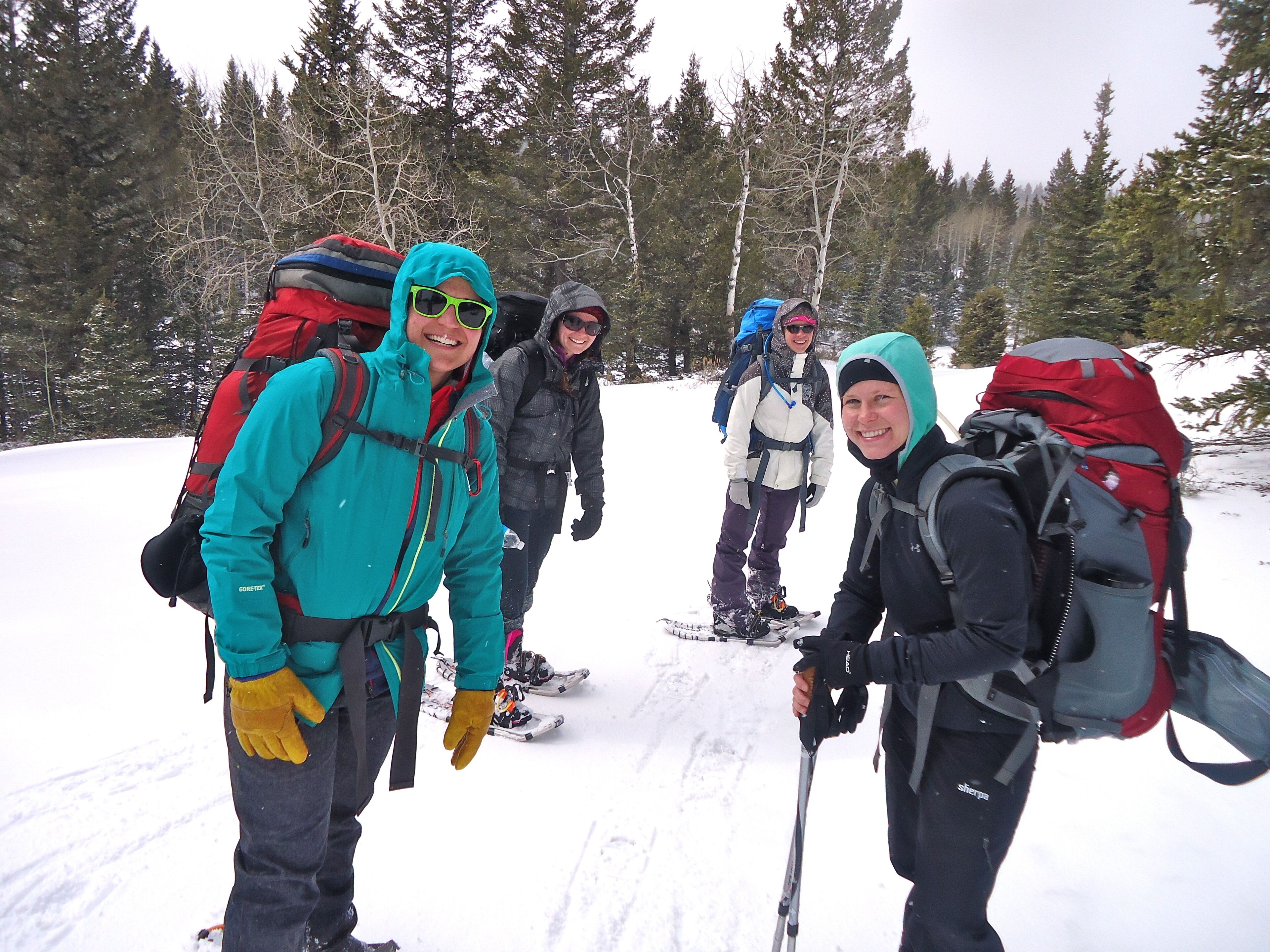 A group of people with backpacks and skis in a snowy forest.