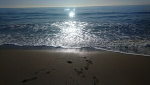 Una playa con huellas en la arena y olas acercándose a la orilla.