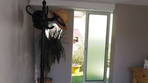 A room with a sliding glass door leading to a garden, a black floor lamp, and a wooden table. - STUDIO FULL OF CHARM AND BRIGHT "BETWEEN EARTH AND SEA" SWIMMING POOL, GARDEN SPORTED. (Montady)