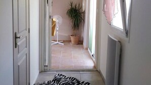 A hallway with a zebra rug on the floor, a potted plant, and a fan in the background. - STUDIO FULL OF CHARM AND BRIGHT "BETWEEN EARTH AND SEA" SWIMMING POOL, GARDEN SPORTED. (Montady)