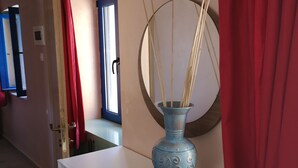 Une pièce avec un meuble blanc, un vase bleu orné de motifs décoratifs et un miroir au mur.