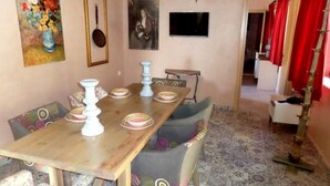 Un coin repas avec une table en bois, des chaises à motifs et un tableau accroché au mur.