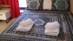 Un lit avec une literie à motifs, deux oreillers et des serviettes pliées.