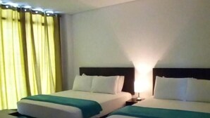 Et hotelværelse med to senge, et natbord og en lampe.