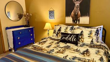 Ein Schlafzimmer mit einem Bett, einem Schminktisch, einem Spiegel, einer Lampe und einem Hirschposter.