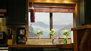 A kitchen with a window, a hanging light fixture, and a coffee maker.