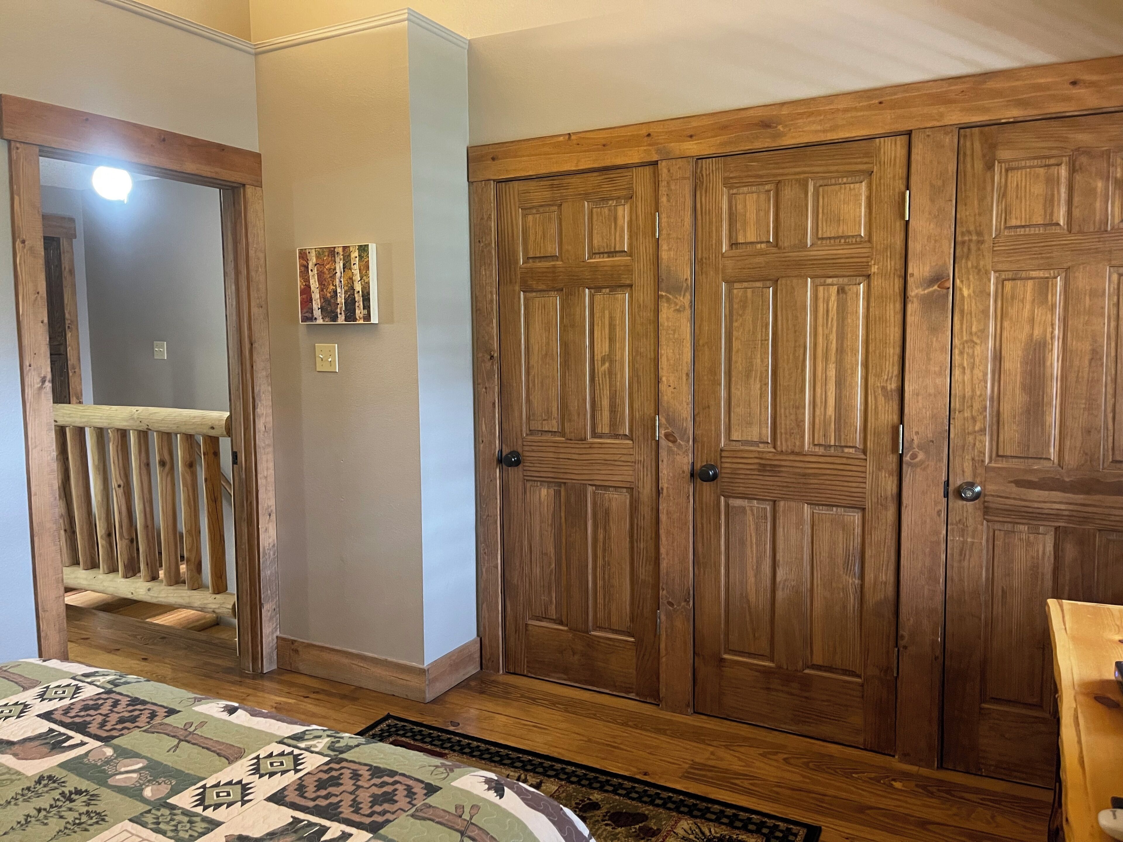 A bedroom with a large wooden wardrobe, a wooden bench, and a patterned rug.