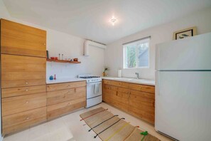 A compact kitchen with wooden cabinets, a gas stove, a sink, and a refrigerator. - Cabin #7 - The Perch at Twin Peaks (Twin Peaks)