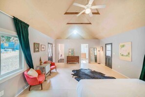 A spacious bedroom with a large bed, a ceiling fan, and a view of the outside.