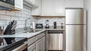 A modern kitchen with white cabinetry, stainless steel appliances, and a granite countertop.