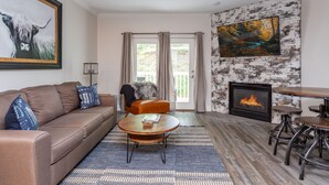 A living room with a brown leather sofa, a round coffee table, a fireplace, and a large painting on the wall.