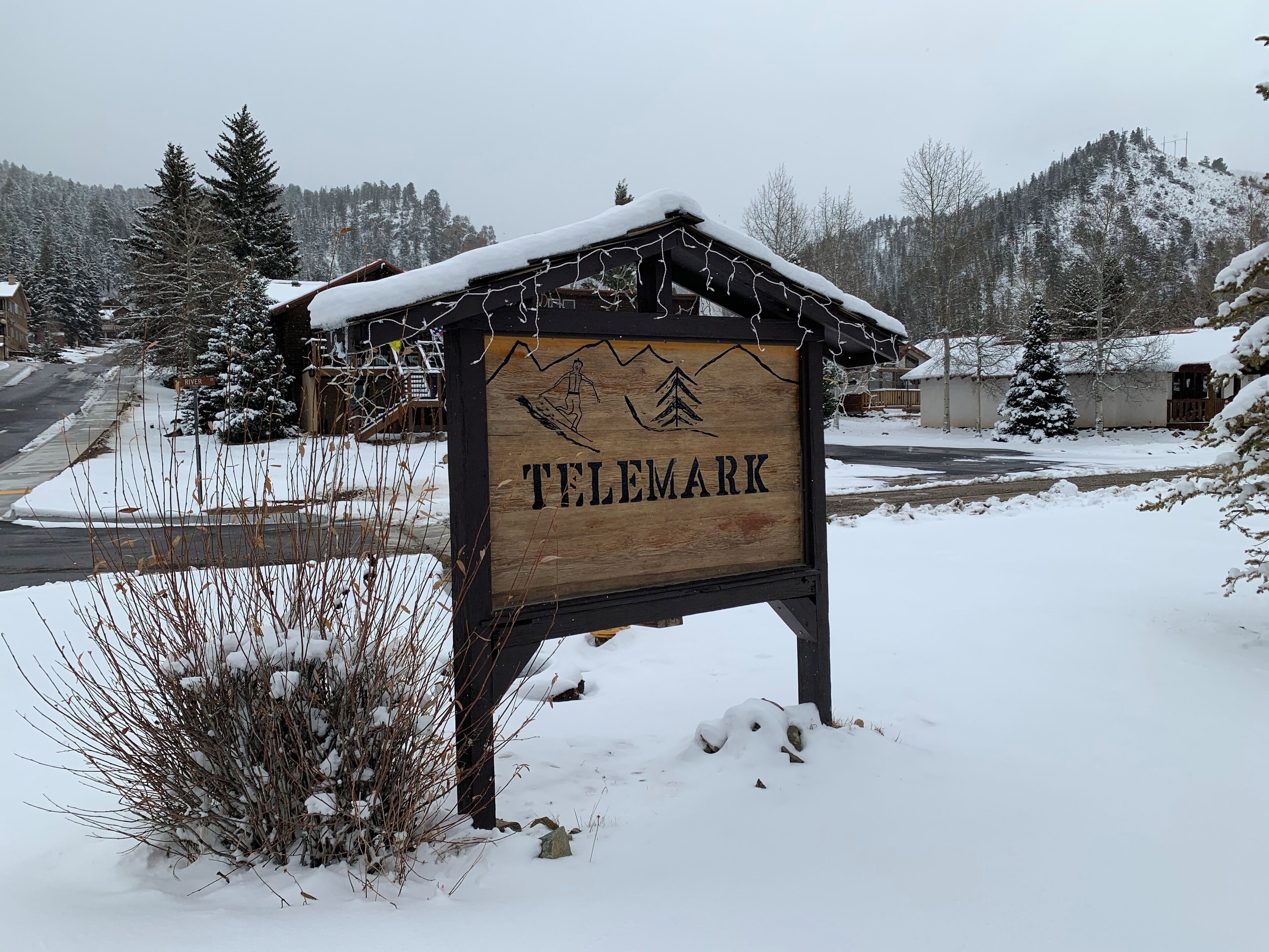 Een houten bord met de tekst 'TELEMARK' en een berg- en boomafbeelding.