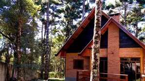 Une cabane en bois, dotée d’un toit en pente, entourée de grands arbres.