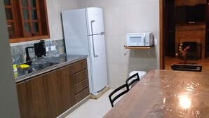 Une cuisine équipée d’un réfrigérateur, d’un four à micro-ondes, d’un évier et de meubles de rangement en bois.