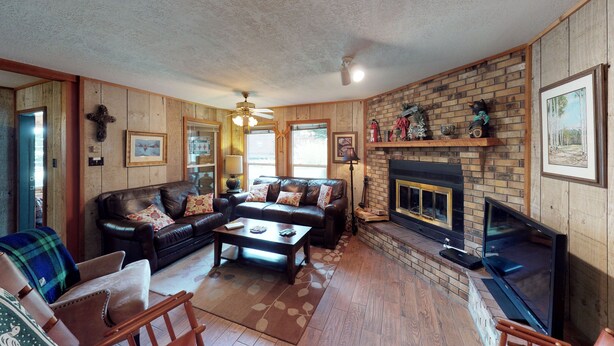 A cozy living room with a fireplace, leather sofa, and a television. - Casa Rio on the River (Red River)