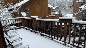 A snow-covered balcony with metal chairs and a wooden railing. - Casa Rio on the River (Red River)