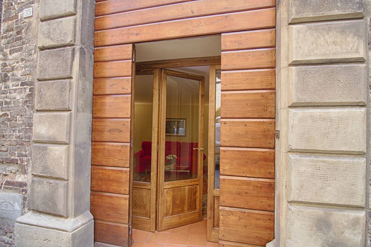 Una puerta de madera con un panel de vidrio, que da a una habitación con una silla roja y una mesa.