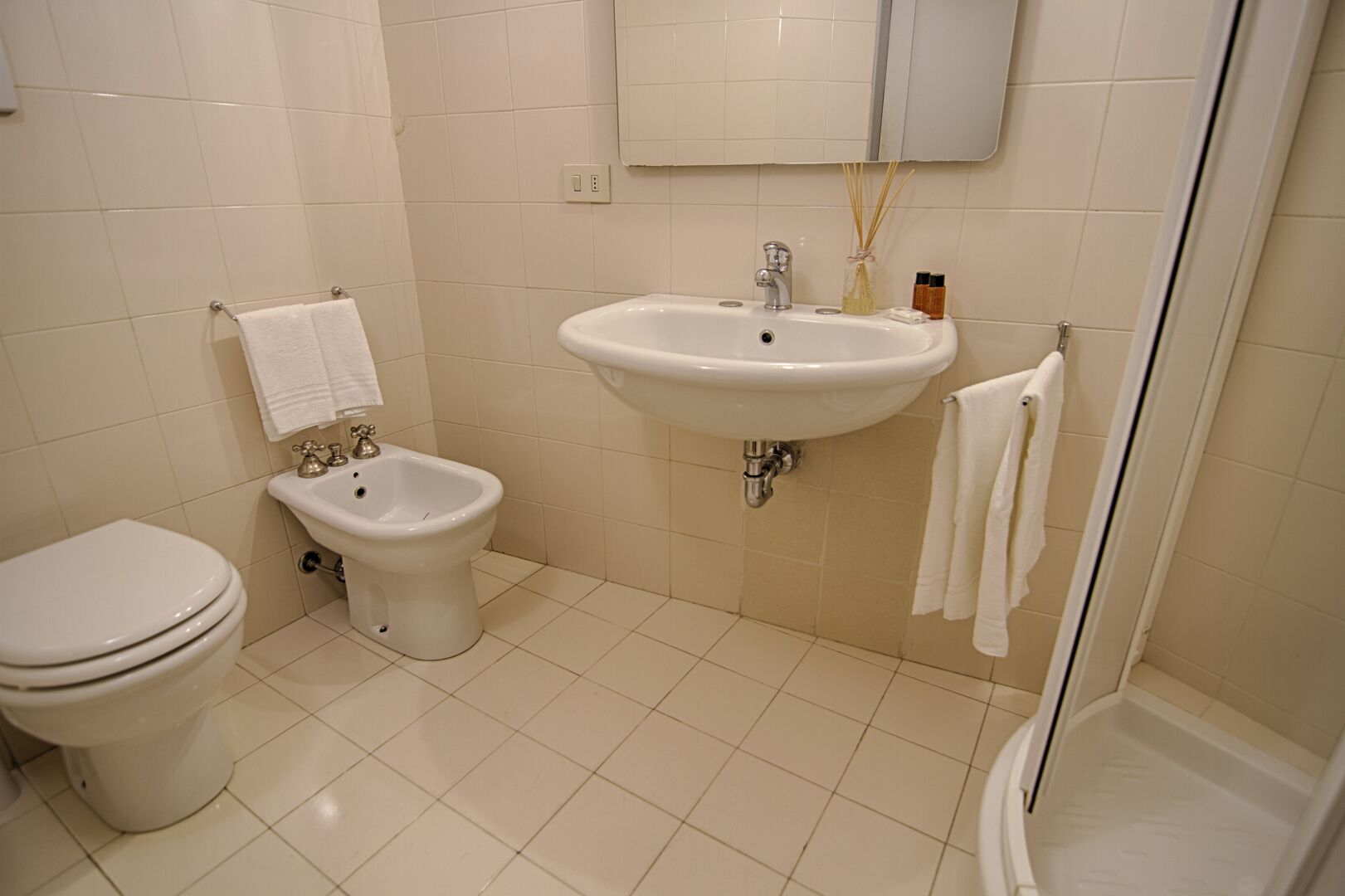 Ein Badezimmer mit Toilette, Bidet, Waschbecken und einer Duschkabine aus Glas.