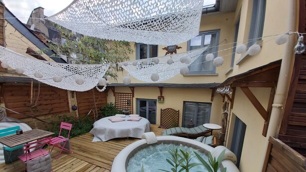 A wooden deck with a hot tub, a lounge chair, and a table with chairs. - Le Patio de Luchon (Bagneres-de-Luchon)