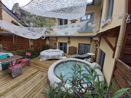 A wooden deck with a hot tub, a lounge chair, and a table with chairs.
