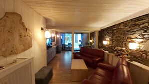 A modern interior with a stone wall, leather sofas, and a wooden ceiling. - Le Patio de Luchon (Bagneres-de-Luchon)