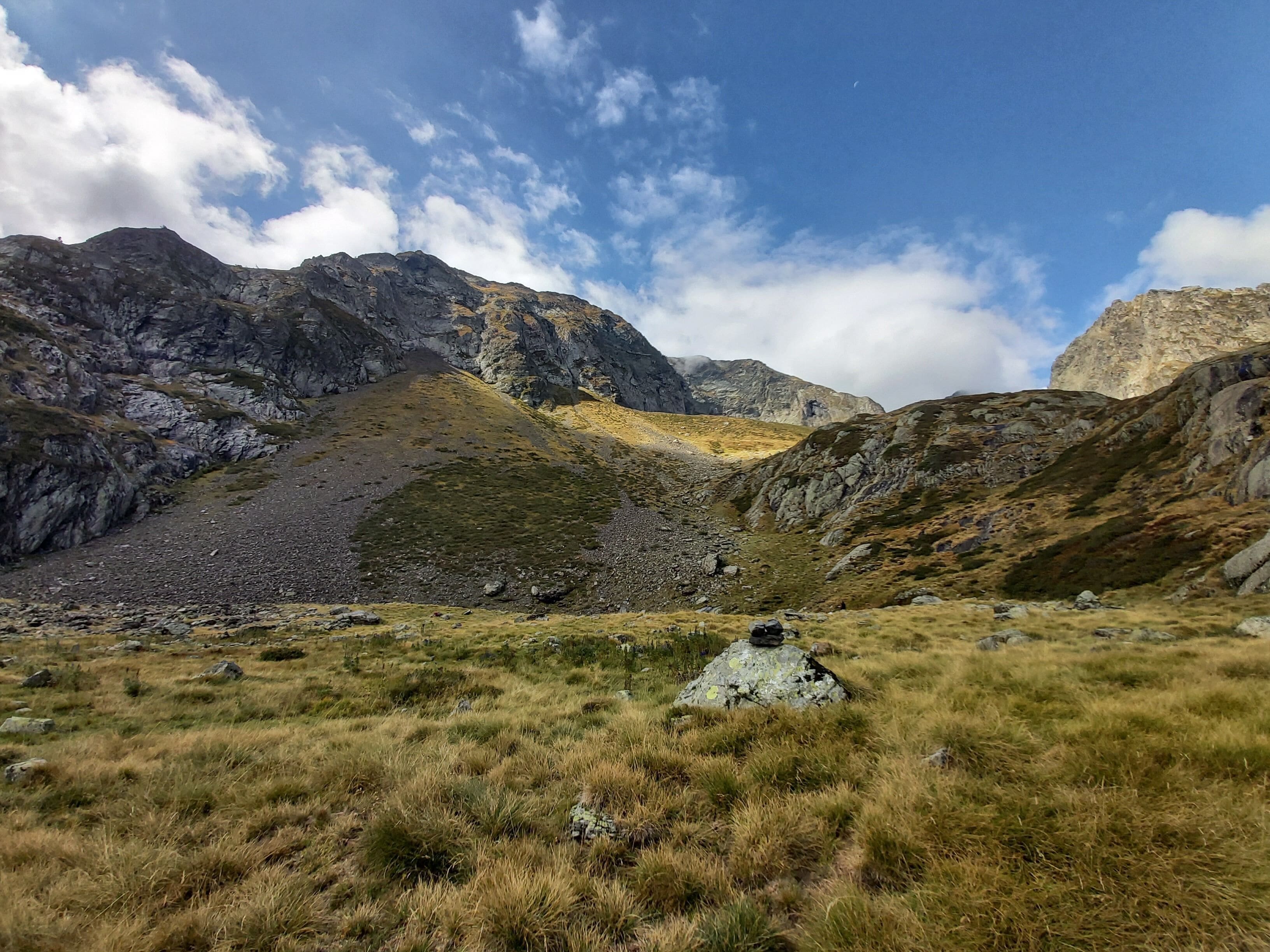 Un paisaje montañoso con terreno rocoso y poca hierba.
