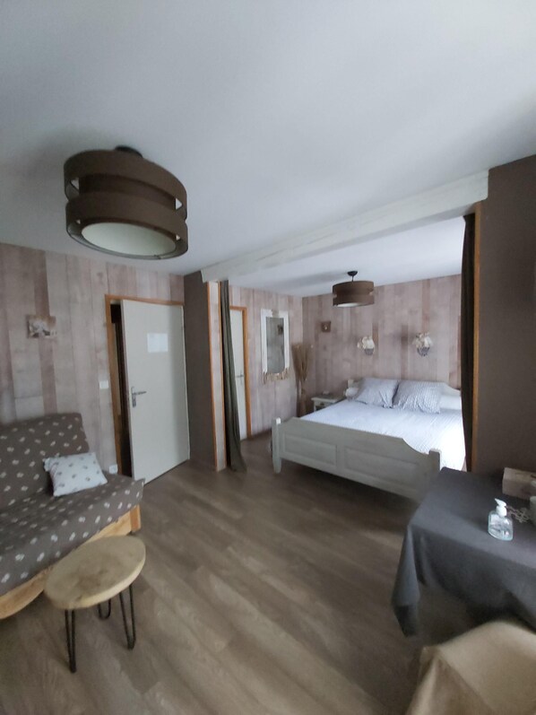 A hotel room with a bed, a sofa, a small table, and a chair.