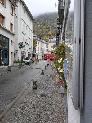 A street view with a hotel, a parked truck, and a mountain in the background. - Le Patio de Luchon (Bagneres-de-Luchon)
