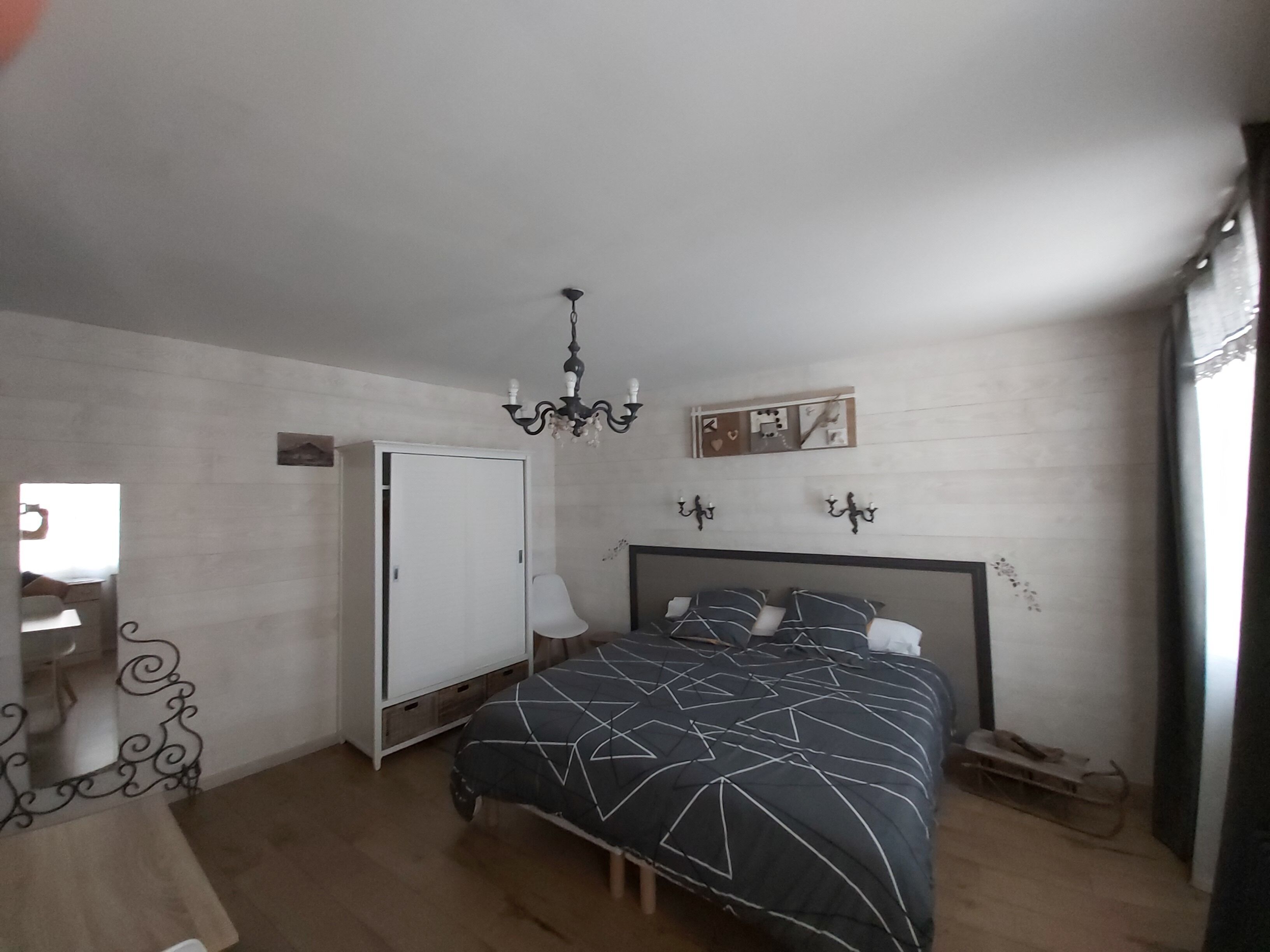 Une chambre à coucher avec un lit, une armoire, un lustre et un miroir.