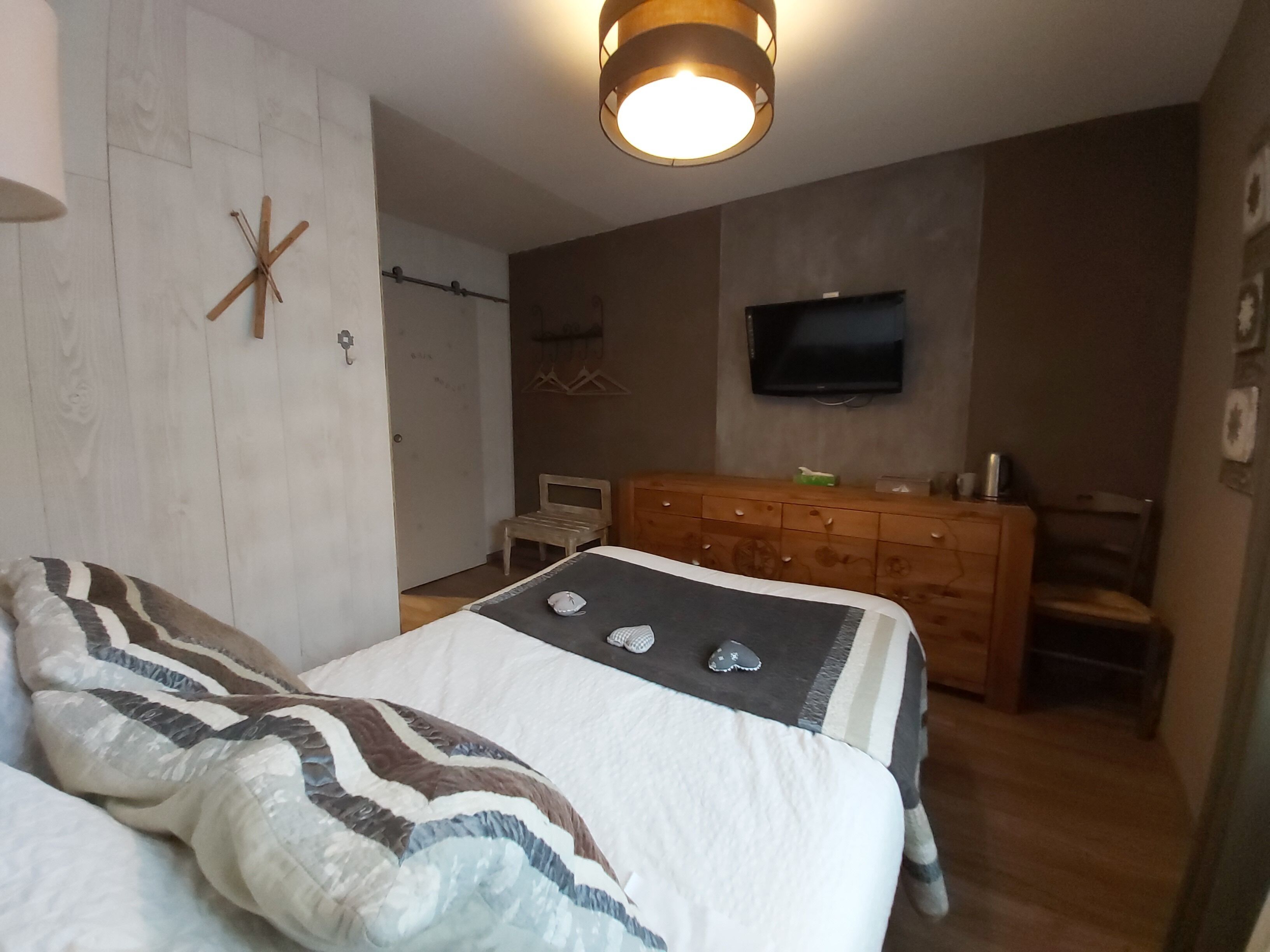 Ein Schlafzimmer mit Bett, Kommode und Fernseher.