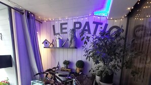 A room with a bicycle, plants, and a sign reading "LE PATIO". - Le Patio de Luchon (Bagneres-de-Luchon)