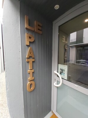 En dør med store bogstaver, der siger "LE PATIO", der angiver et patioområde.